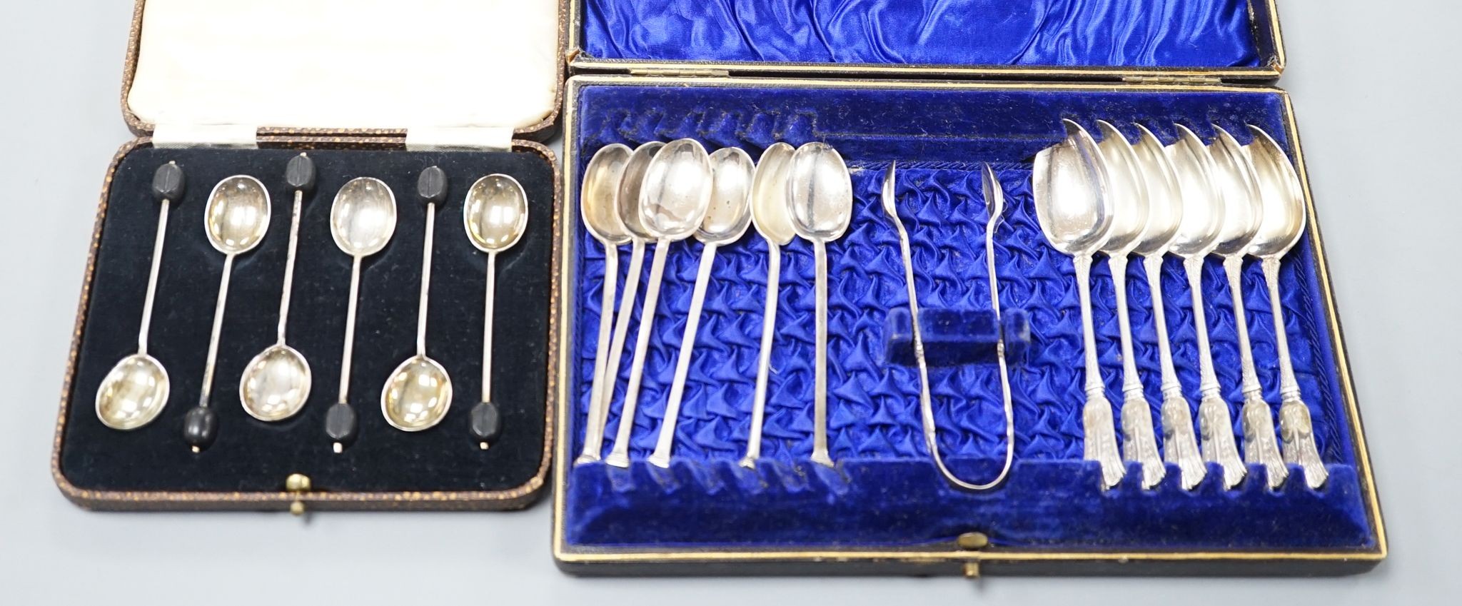 A cased set of six silver bean end coffee spoons, two other sets of six teaspoons and a pair of silver sugar tongs.